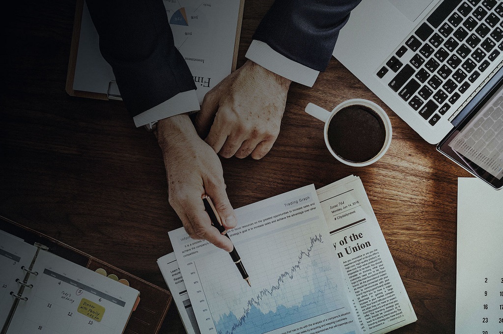 Investment web page Featured Image - Picture of an investment broker explaining an investment portfolio performance graph (View from above)