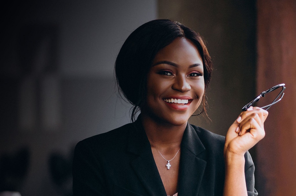 Key Person Cover web page Featured Image - Picture of a Female African Business woman, smiling and holding her eye glasses